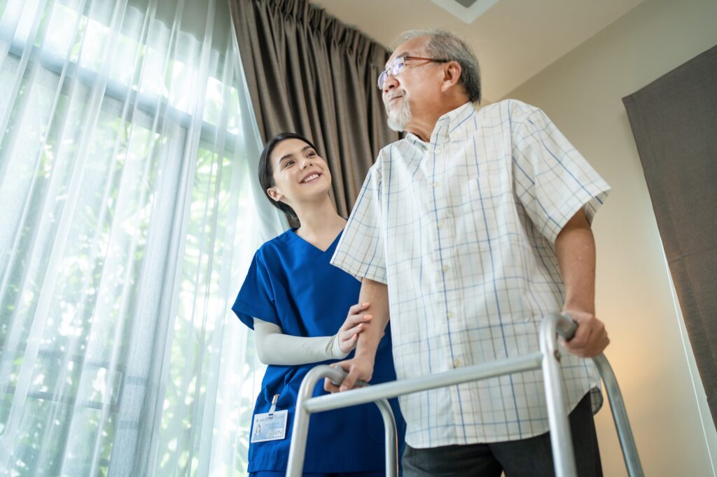 Asian Senior elderly disabled man patient walking slowly with walker at nursing home care.